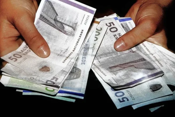 To hænder, der tæller kontanter. Repræsenterer udbetalt løn.