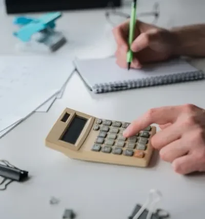 Der regnes på en lommeregner og skrives tal ned i en notesbog.